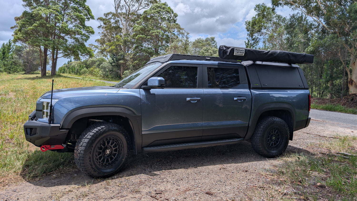 Gray BYD Shark 6 with a roof rack on a dirt road